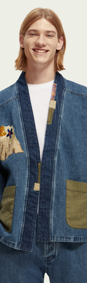 A man wearing a Scotch & Soda Japanese style denim jacket and matching pants with floral designs sewn on