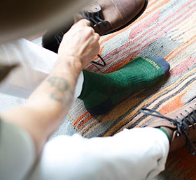 A man putting on a green Wigwam wool sock