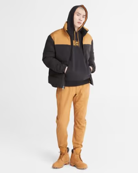 A man wearing a timberland outfit with a brown jacket, pants and boots
