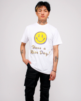 A man wearing a white smiley face Chinatown Market t-shirt and black pants