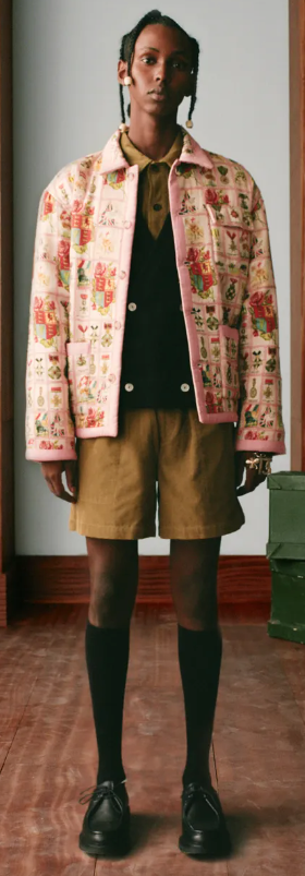 A man wearing a pink floral print Bode jacket, brown shorts and high black socks