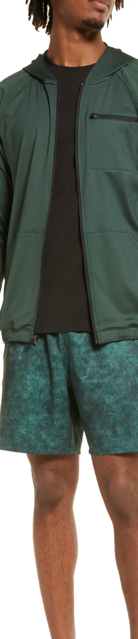 A man standing in a green Zella by Nordstrom jacket and shorts