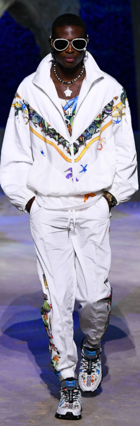 A man wearing a white Versace tracksuit with colorful print and matching sneakers