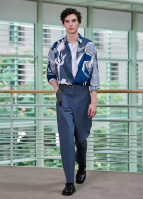 A man wearing a blue Hermes button up with blue pants