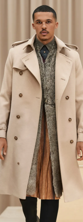 A man wearing a light brown Burberry trench coat with a large floral jacket underneath