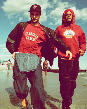 Two men walking on the beach wearing red QuarterSnacks Sweatshirts and baggy pants