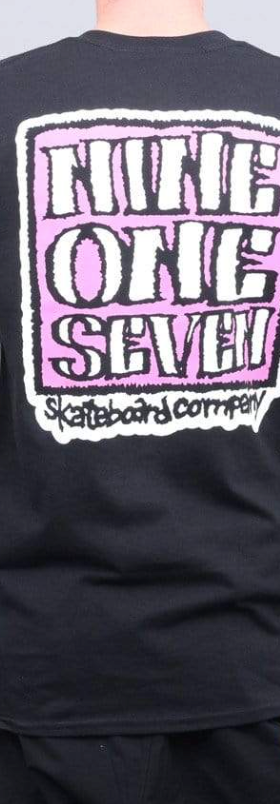 A man wearing a Call Me 917 t-shirt with a large print on the back in pink and white