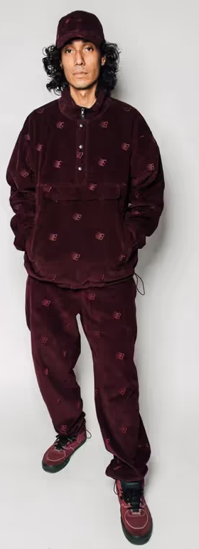 A man wearing a Bronze 56k black fleece with matching pants and red nikes