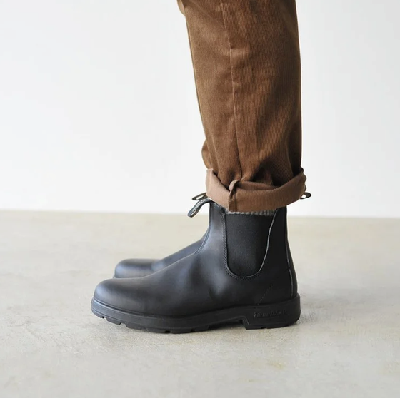 A close up of a pair of black classic Blundstones on someones feet