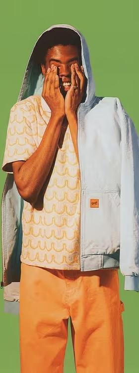 A man wearing a Golf Wang baby blue jacket and an orange button up with matching pants