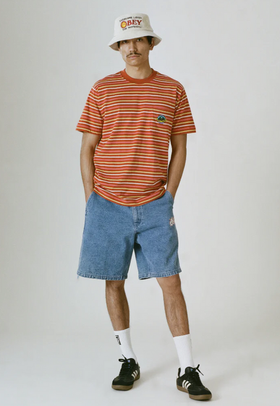 A man wearing a striped obey t-shirt with a branded bucket hat and denim shorts
