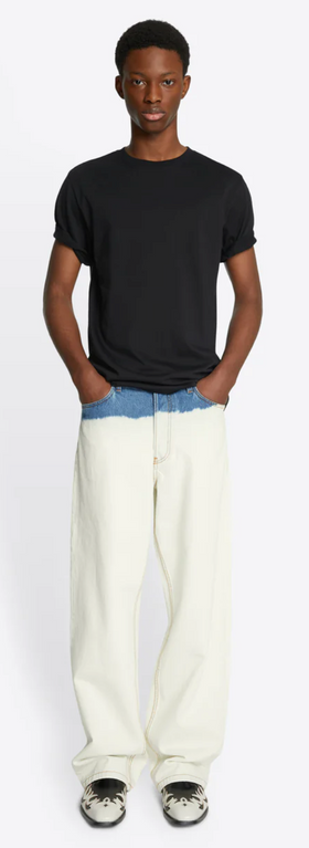 A man wearing a slim fit Dries Van Noten navy blue t-shirt with baggie white denim
