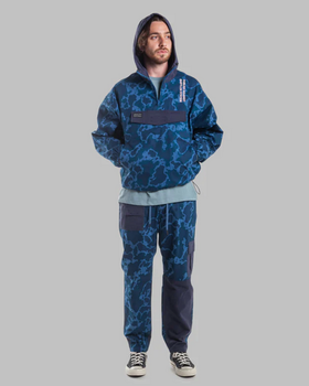 A man wearing a camo print Publish Brand hoodie and sweats