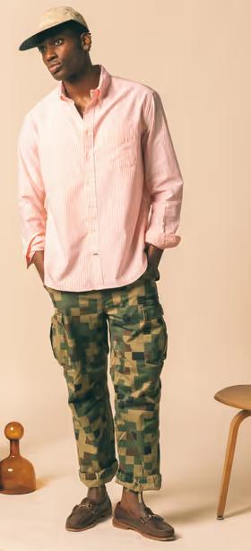 A man wearing a Gitman Vintage outfit featuring a pink button up shirt and camo pants
