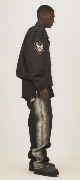 A man wearing a Heron Preston outfit featuring a coaches jacket and baggy jeans