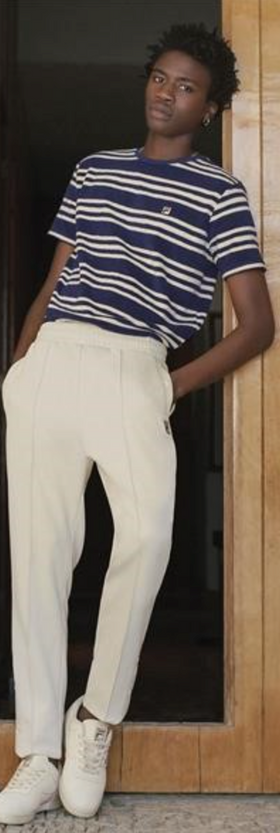 A man wearing a Fila outfit with a striped t-shirt and white pants