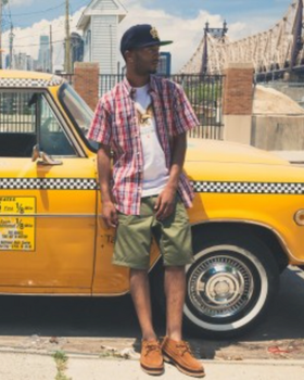A man wearing a Acapulco Gold plaid button up with a white t-shirt and green shorts