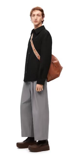 A man wearing a Loewe sweater and grey wide pants