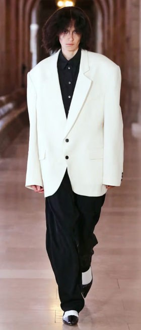 A man wearing a designer Marc Jacobs white suit jacket and black pants