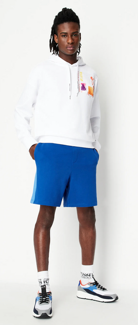 A man wearing a white Armani Exchange hoodie and blue shorts