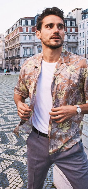 A man wearing a floral Bonobos button-up with a white t-shirt and grey slacks