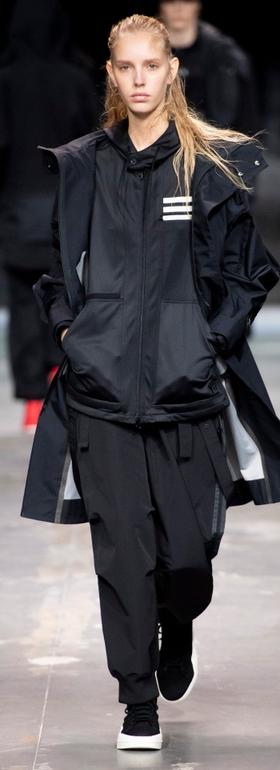 A man wearing a Y-3 black technical outfit walking the runway