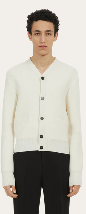 A man wearing a white Ferragamo cardigan and black pants