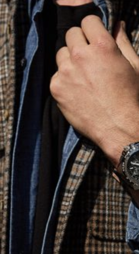 A man wearing a black Citizen Watch and a plaid jacket