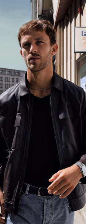 A man wearing a Tissot silver watch and a black jacket
