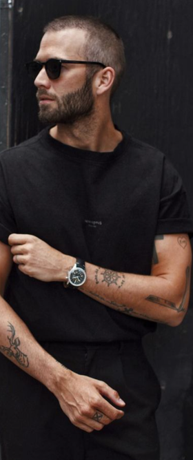 A man wearing a Breitling watch with a black t-shirt and sunglasses