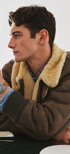 A man wearing a silver Timex and a brown jacket