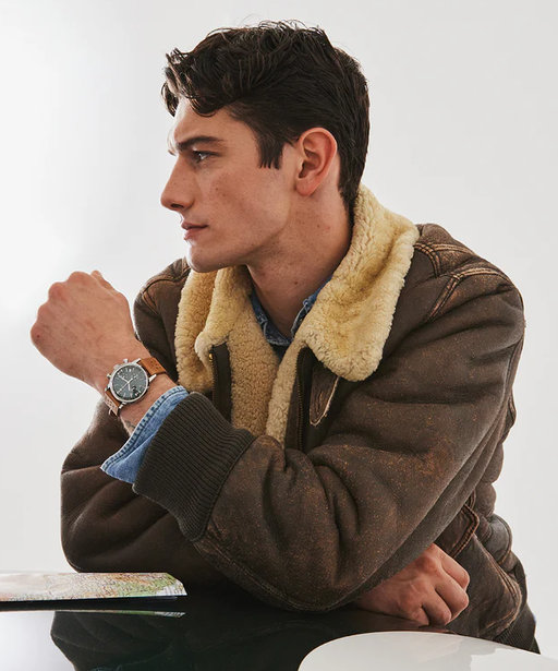 A man wearing a silver Timex and a brown jacket